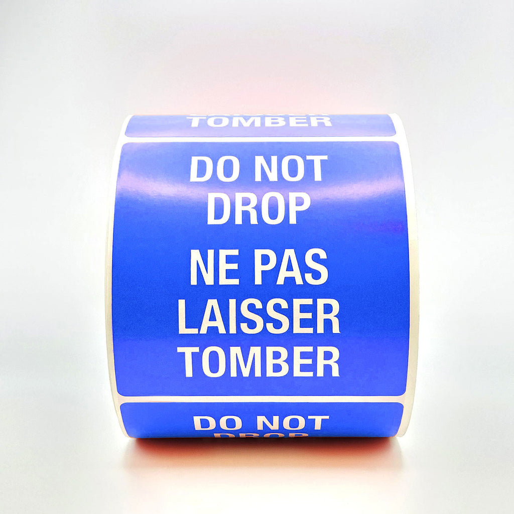 A roll of blue labels with 'DO NOT DROP' text in both English and French, indicating the labels are bilingual.