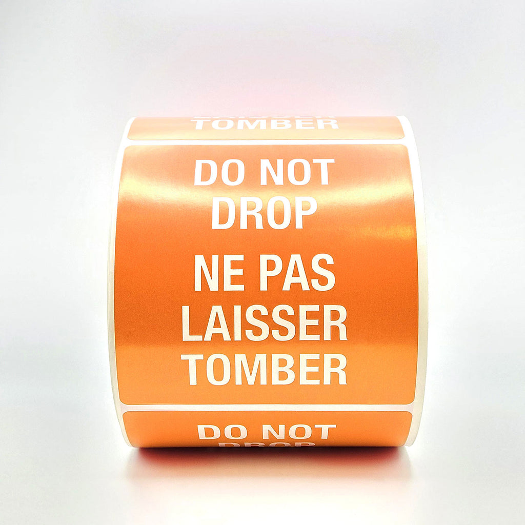 A roll of orange labels with 'DO NOT DROP' text in both English and French, indicating the labels are bilingual.
