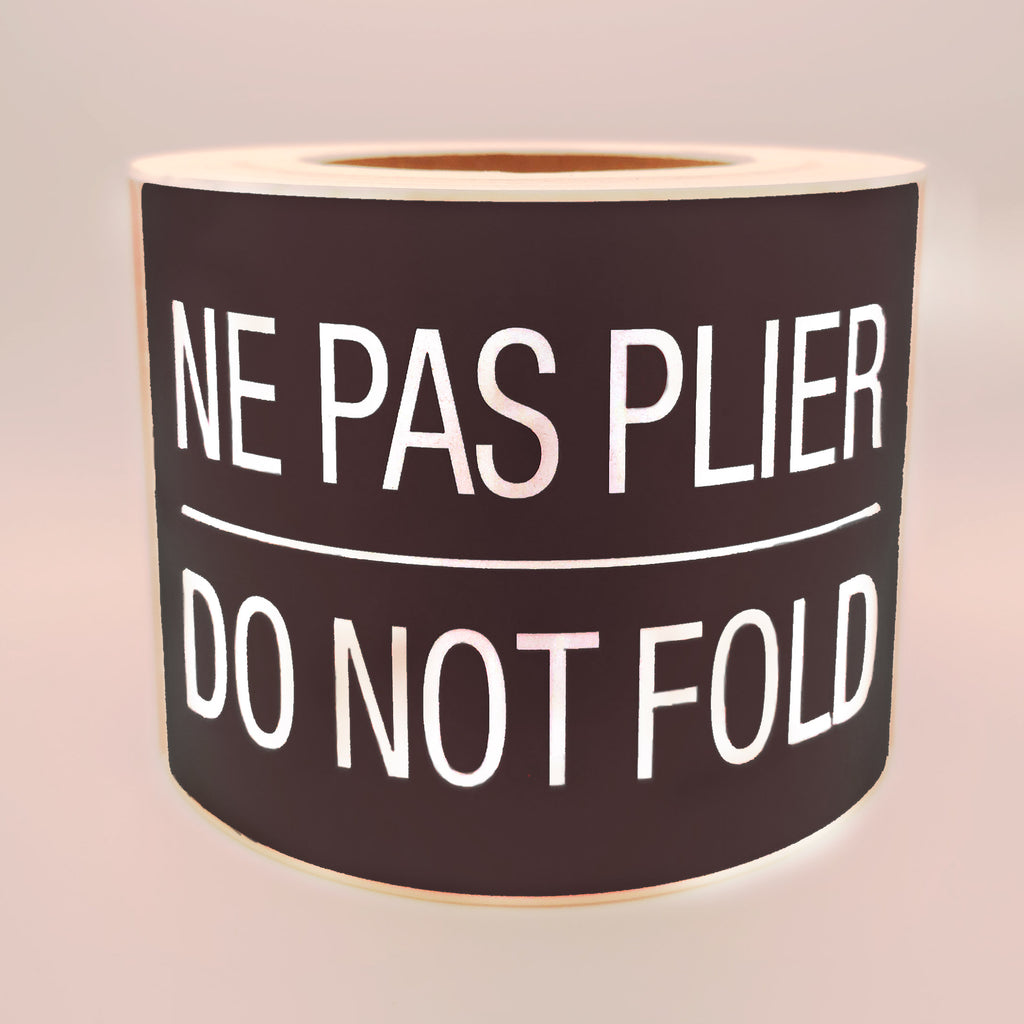 Roll of black labels with white text 'NE PAS PLIER DO NOT FOLD' on a white background
