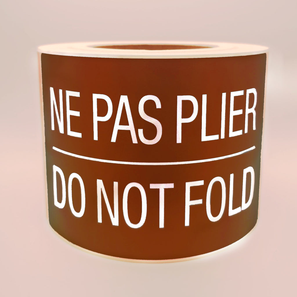 Roll of brown labels with white text 'NE PAS PLIER DO NOT FOLD' on a white background