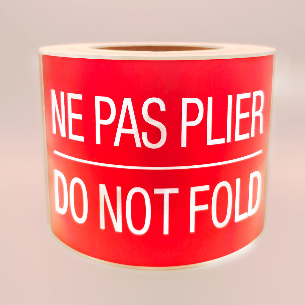 Roll of red labels with white text 'NE PAS PLIER DO NOT FOLD' on a white background