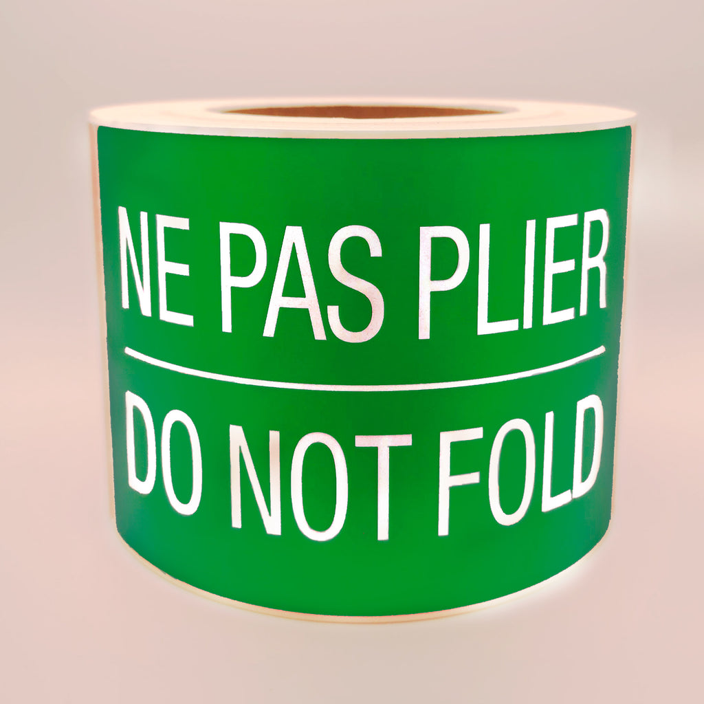 Roll of green labels with white text 'NE PAS PLIER DO NOT FOLD' on a white background