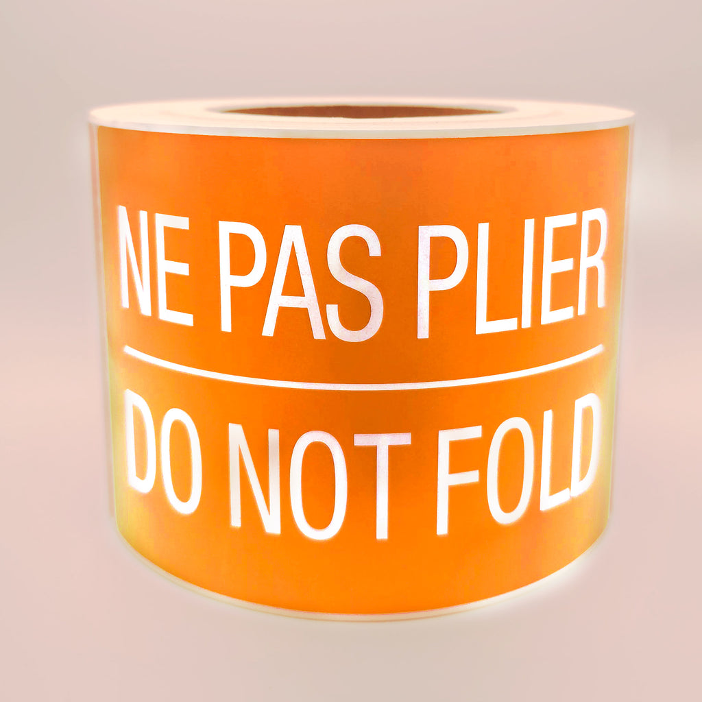 Roll of orange labels with white text 'NE PAS PLIER DO NOT FOLD' on a white background