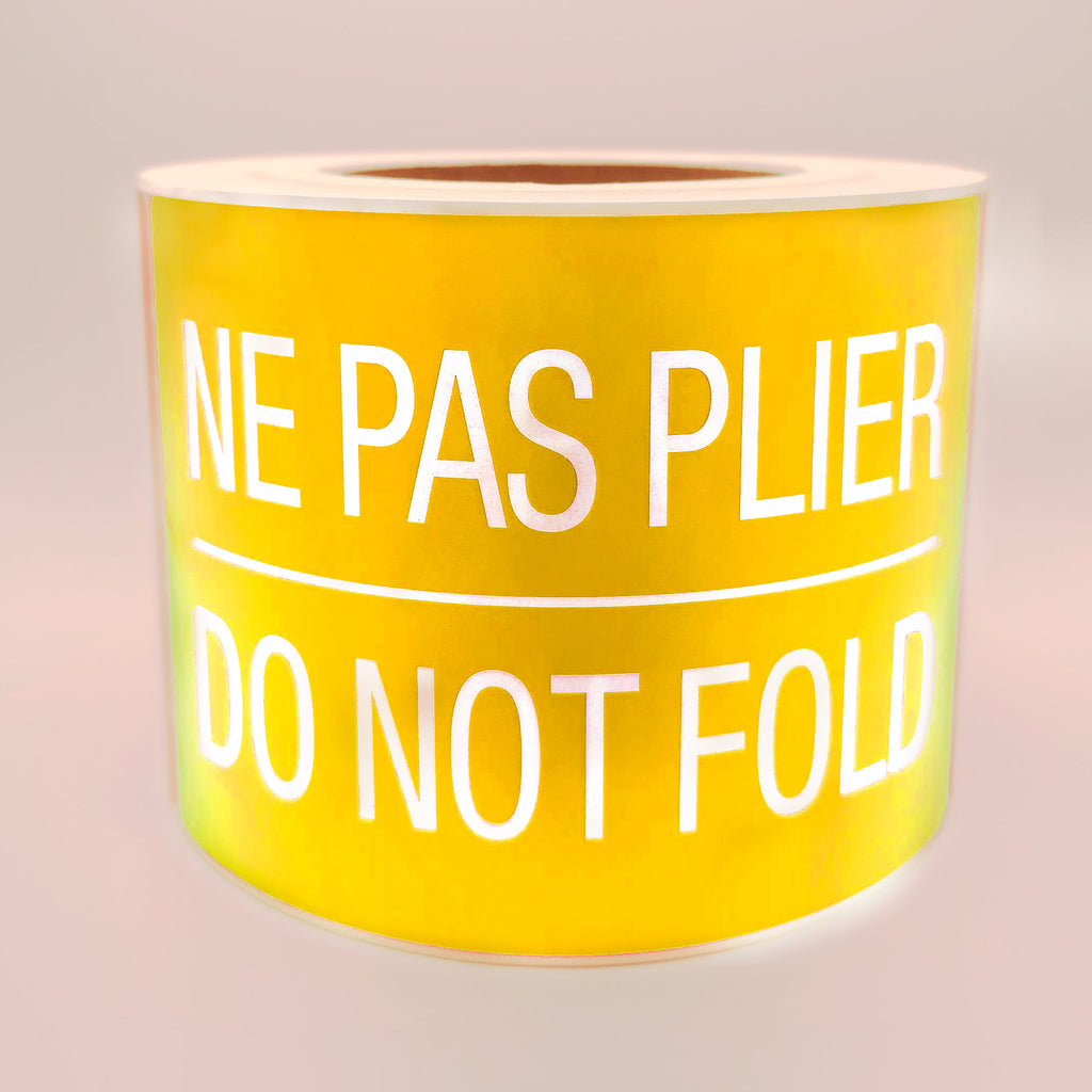 Roll of yellow labels with white text 'NE PAS PLIER DO NOT FOLD' on a white background