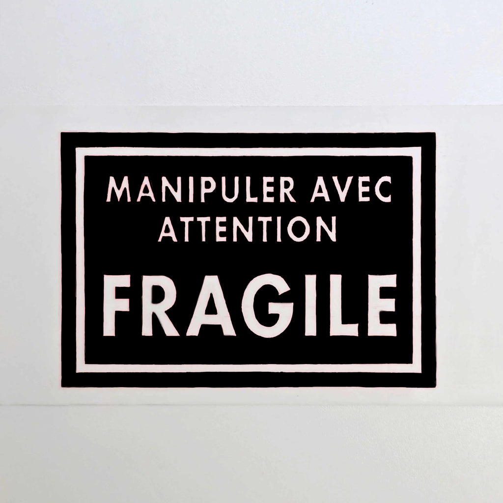 Black and white sign with text 'Manipuler avec attention FRAGILE' on a white background